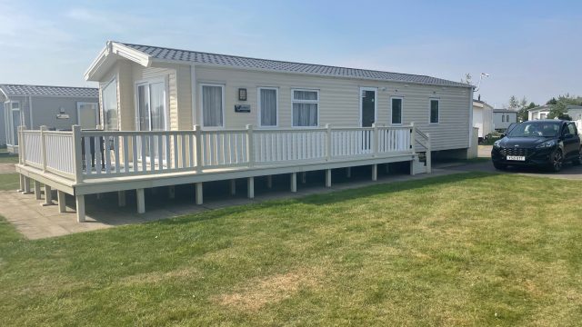 Cream static Caravan on a park with fencing around. Sell my Static caravan.
